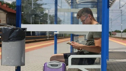 Young man reading book on the train stop while waiting for the arrival Stock Footage 78654957
