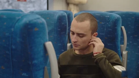 A young man is reading a book on the train looking out the window. winter Stock Footage 199519779