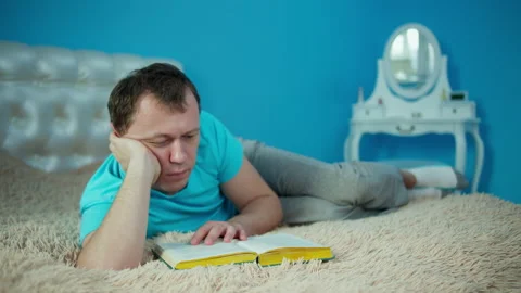 Young man reading a book while lying on the bed Stock Footage 145843487