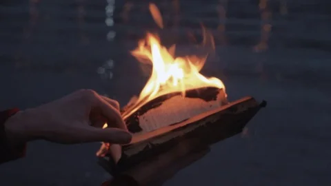 Young man reading burning book standing on coast storm clouds on background Stock Footage 74378700