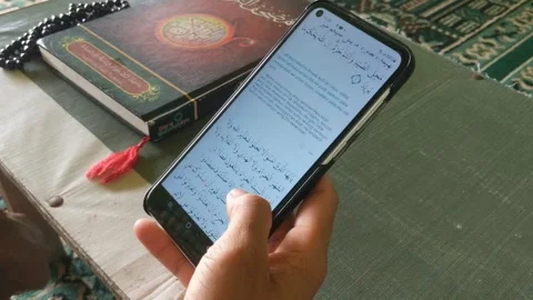 Young man reading digital Koran on android Stock Footage 265074504