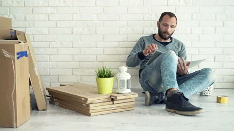Young man reading documents sitting on floor at his new home Vídeo Stock 63464888