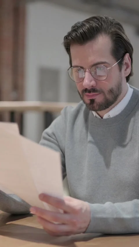 Young Man Reading Documents while Sitting in Office, Vertical Video Stock Footage 339581055
