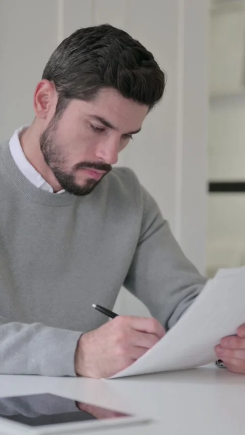 Young Man Reading Documents while Sitting in Office, Vertical Video Stock Footage 339582392