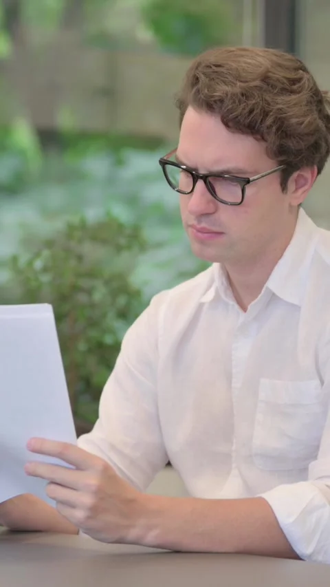 Young Man Reading Documents while Sitting in Modern Office, Vertical Video Stock Footage 340032743