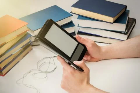 A young man is reading an e-book on the background of old paper books. Foto stock