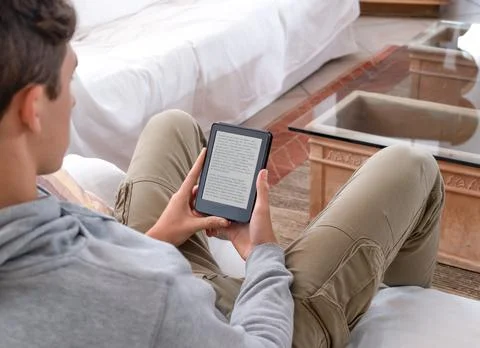 Young man reading an e-book on digital tablet device Stock Photos