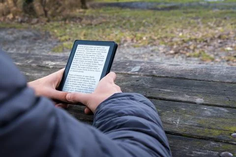 Young man reading an e-book on digital tablet device in outdoor at winter Stock Photos