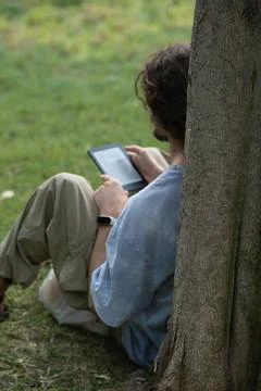 Young Man Reading E-Book in the park Fotos de archivo