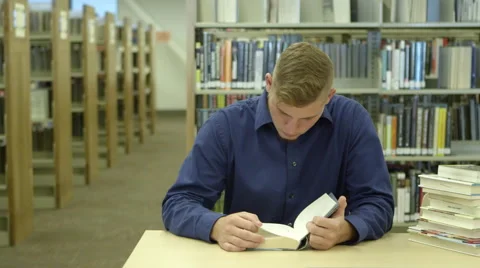 Young man reading in library Stock Footage 67364704