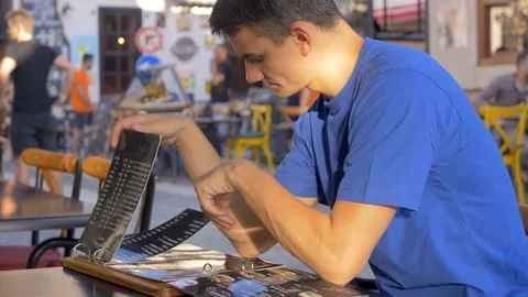 Young man reading menu at cafe Stock Footage 106398834