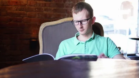 Young man reading menu sitting in cafe Stock Footage 73126674