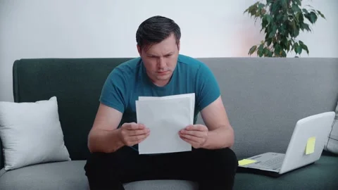 A young man reads documents while sitting on the couch. Stock Footage 148570764