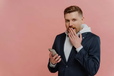 Young man receiving shocking message on smartphone Foto stock