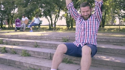 Young man recives good message and he is happy, sitting on stairs. 库存影片 67240064
