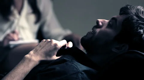 Young man reclining on a couch talking to his psychiatrist explaining some Stock Footage 32945413