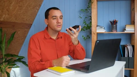 Young man recording voice message on smartphone in home office Video stock 148228019