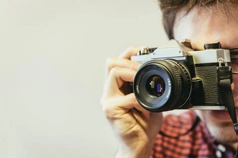 Young man in red-blue checked shirt is taking a picture with an vintage camera, Stock Photos