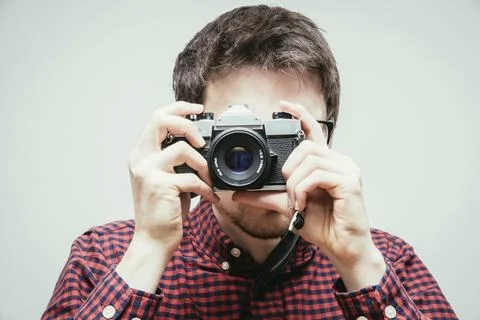 Young man in red-blue checked shirt is taking a picture with an vintage camera, Stock Photos