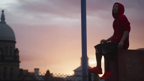 Young man in red clothes sitting on top of the building Stock Footage 264205454