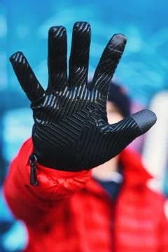 Young man in red, down jacket shows lightweight textured gloves with digital Stock Photos