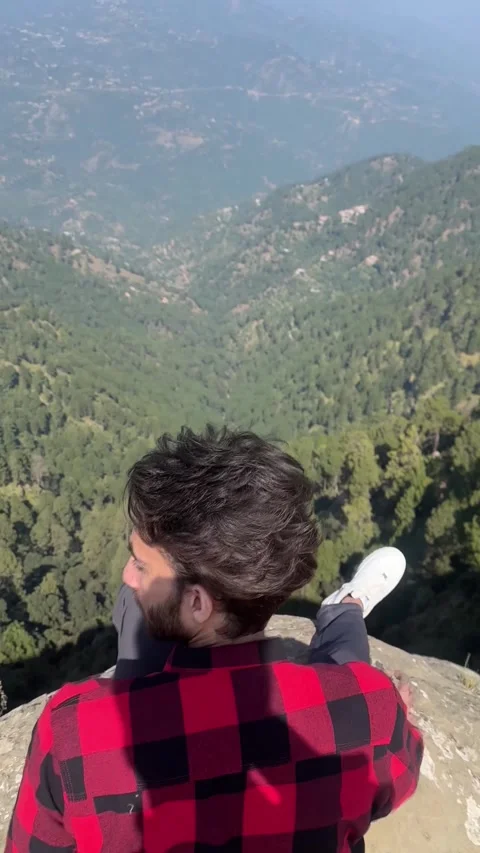Young Man in Red Flannel Sitting on Mountain Cliff Edge at Sunset Stock Footage 330136116