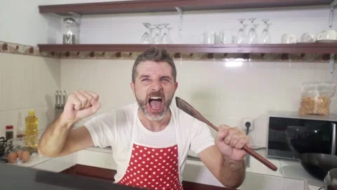 Young man in red kitchen apron singing crazy happy holding spoon Stock Footage 131803318