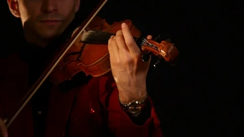 A young man in red suit plays the violin on a black background Stock Footage 88871813