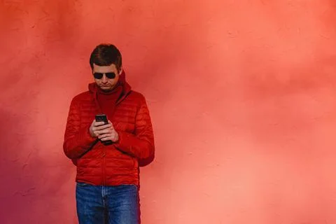 Young man in red sweater, using his smart phone Stock Photos