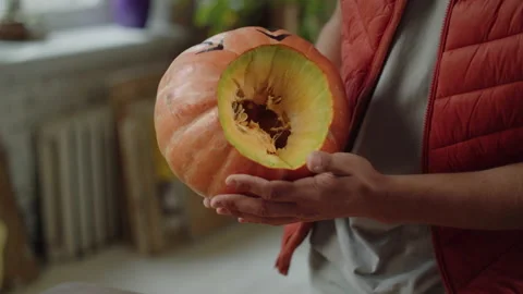 A young man in red vest is turning a halloween pumpkin Stock Footage 170406413