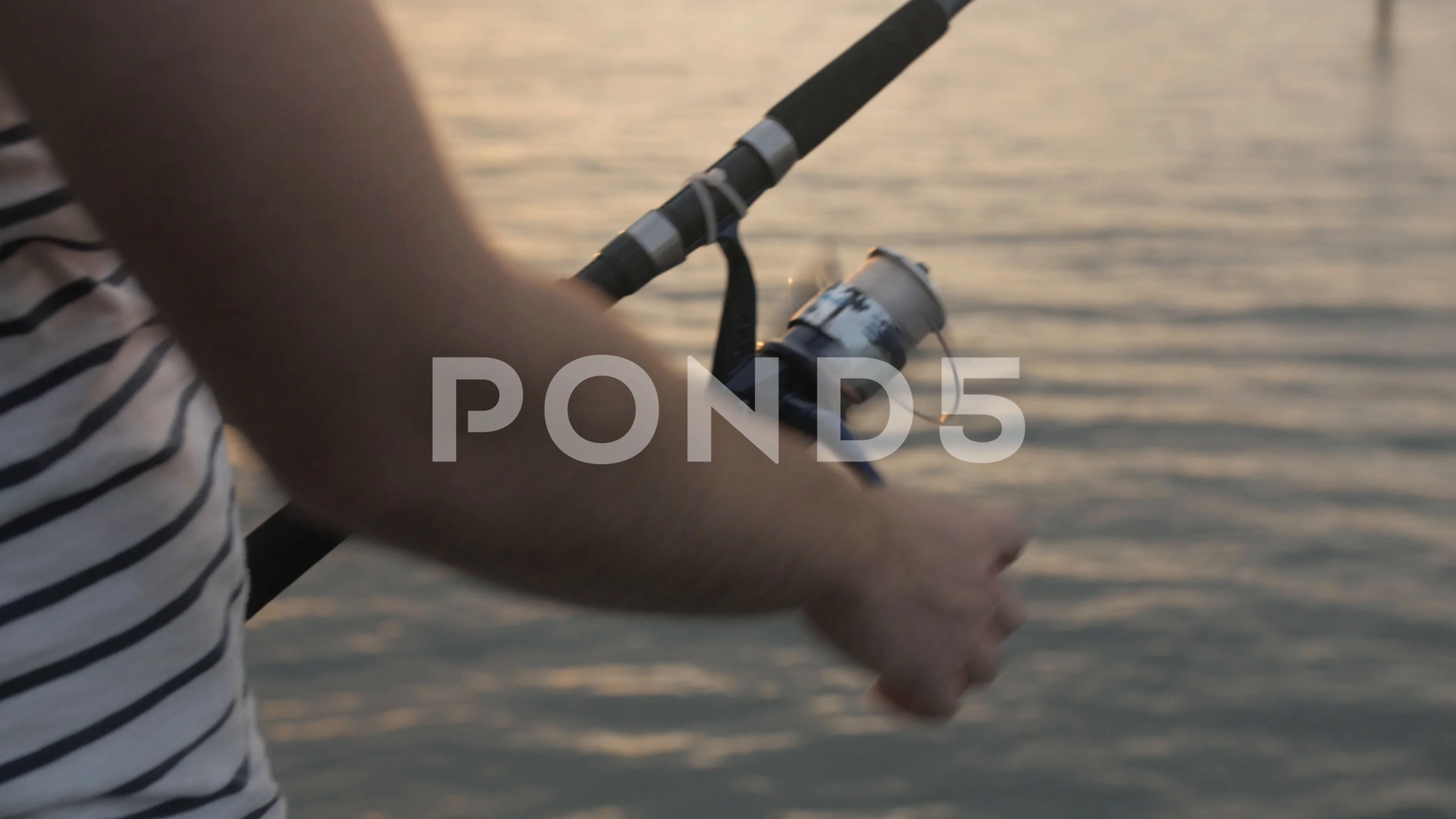Young man reeling in a fishing line at s, Stock Video