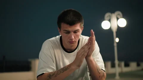 Young Man Reflecting at Night Under Street Lamps in Urban Setting Vídeo Stock 301701713