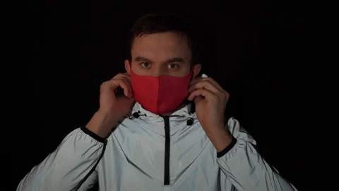 Young man in a reflective jacket puts on a red medical mask and looks into the Stock Footage 150787504