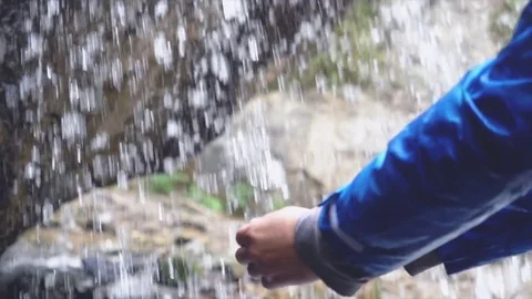 Young man refreshing his face and drinking water in stream of waterfall in Slow Stock Footage 80348328