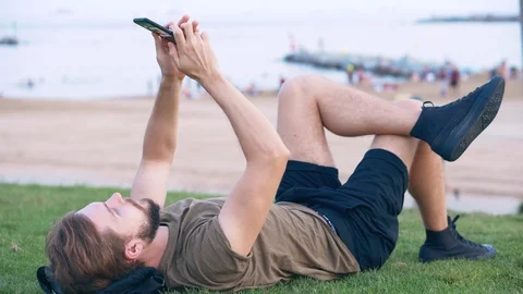 Young Man Relaxed Using Smartphone and Chatting on the Beach Stock Footage 118919465