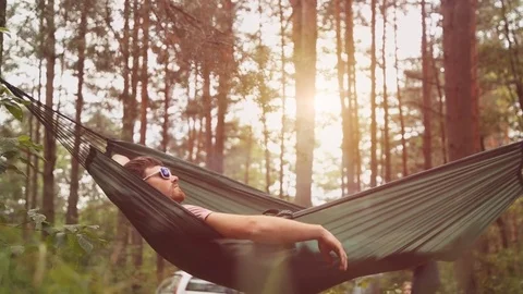 A young man relaxes on a hammock in the forest. Stock Footage 79751561
