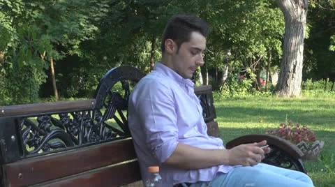 Young man  is relaxes in the park ,using touchscreen tablet Vídeos de archivo 25561450