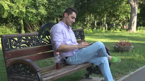 Young man  is relaxes in the park ,using touchscreen tablet Vídeos de archivo 25562041