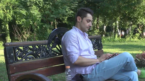 Young man  is relaxes in the park ,using touchscreen tablet Vídeos de archivo 25562169