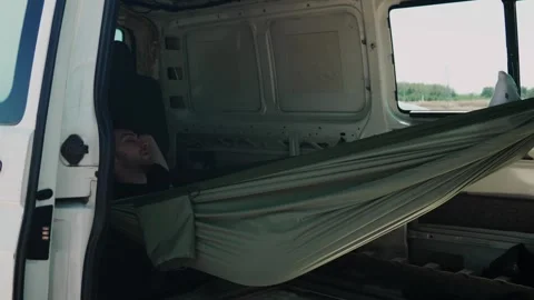 Young Man Relaxing in a Hammock Inside a Van During a Road Trip on a Sunny Day Stock Footage 278731492