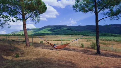 Young man relaxing in hammock with mountain view Video stock 343687839