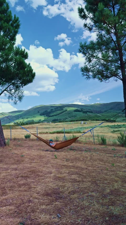 Young man relaxing in hammock while using smartphone Видео 343688189