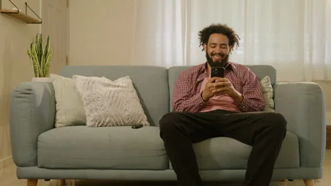 A young man is relaxing on his sofa, browsing the internet and connecting with 库存影片 284707419