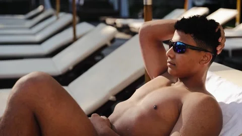 Young man relaxing on resort poolside sun lounger enjoying summer vacation Vídeo Stock 328160182