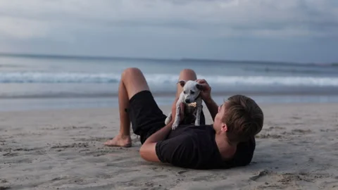 A young man relaxing on a sandy beach at sunset Stock Footage 300076112