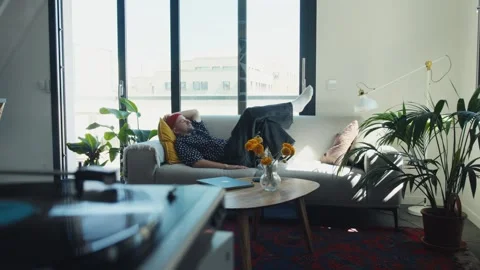 Young man relaxing on sofa after finishing reading Stock Footage 312999328