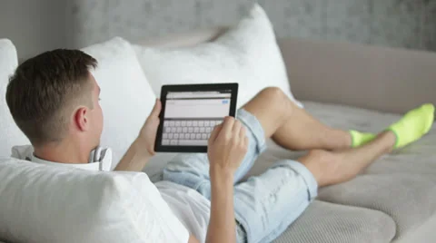 Young man relaxing on sofa with tablet Stock Footage 27691921