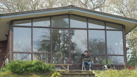 Young man relaxing under cabin porch in woods Stock Footage 305148902