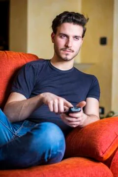Young man with remote control watching TV Stock Photos