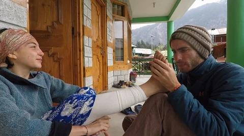 Young man removes splinter from young woman's foot. Attractive couple. Stock Footage 91112185